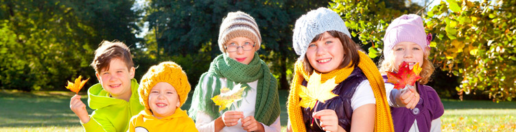 Fröhliche Kinder mit Blättern in den Händen. - die Kinder tragen eine Mütze - helles freundliches Licht